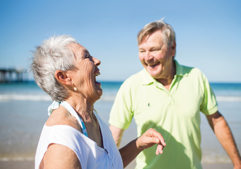 two older people laughing on the beach