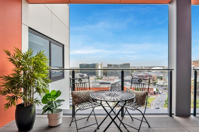Spence on light balcony with views of the city and furniture
