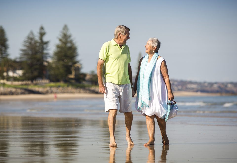 Old couple taking a walk at the beach and getting active