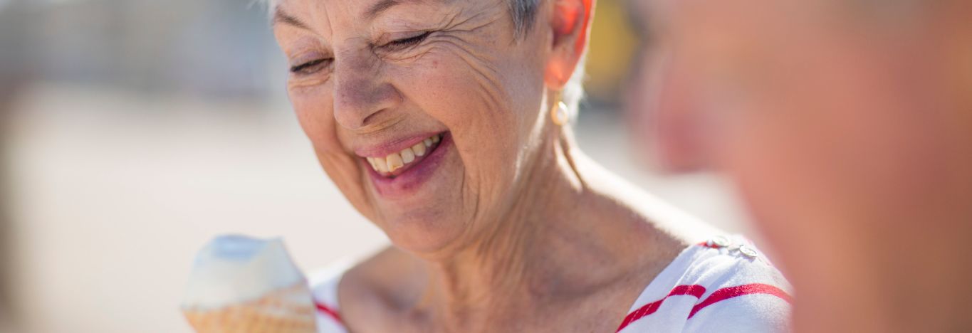 Older lady enjoying ice cream at the beach with a support worker