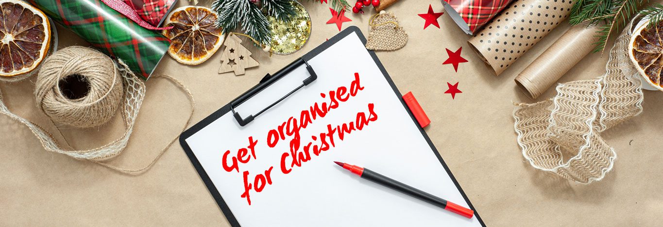 Table with Christmas wrapping paper and notepad with writing on it saying 'get organised for Christmas'