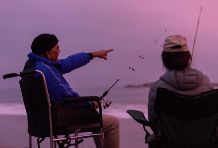 Man on a wheelchair enjoying fishing with his daughter