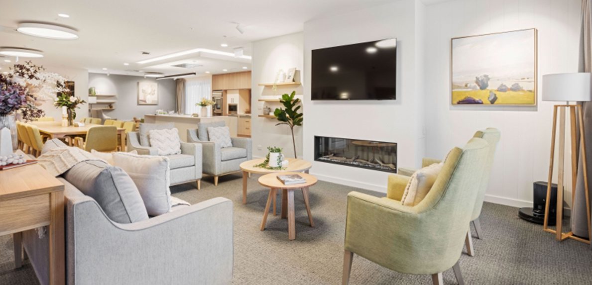 Cosy lounge with fireplace, seating and TV at Healthia Residential Care Home