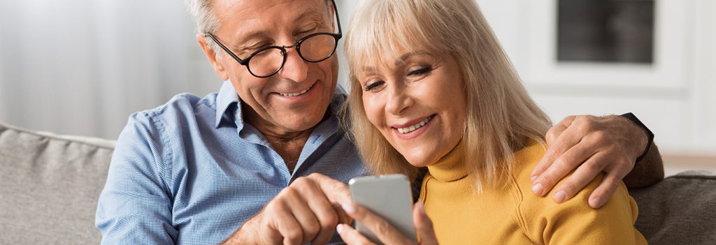 Older couple looking at a mobile phone, downloading apps to exercise the brain