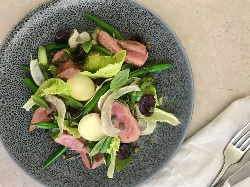 Bowl of lamb and asparagus nicoise salad