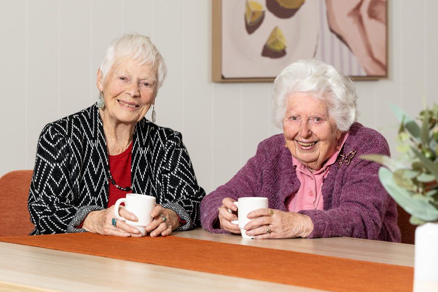 Jean and Rose sitting at a table, having a cup of tea and chat about friendship and life at Healthia.