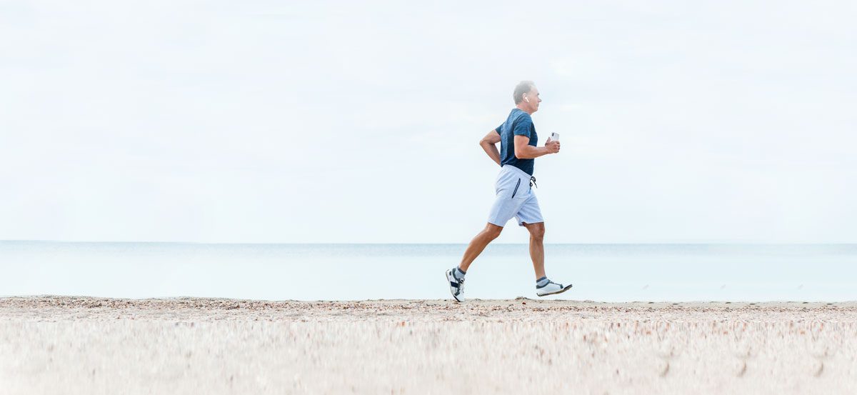 A man walking on the beach in summer, exercising