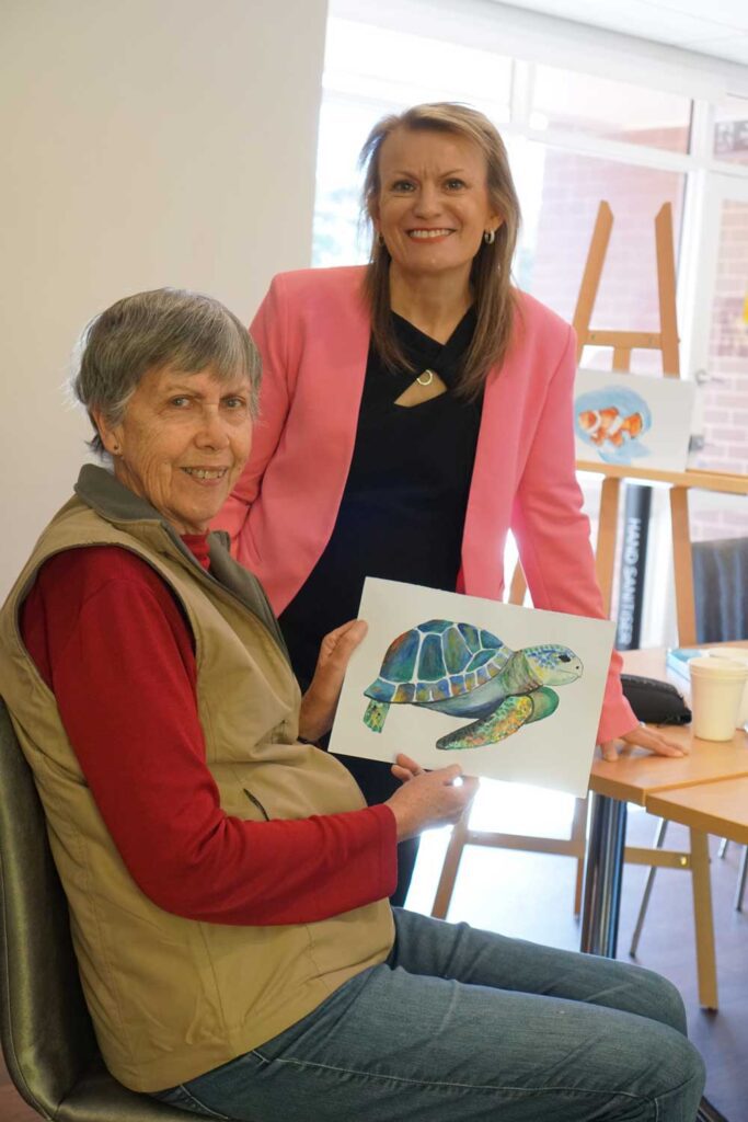 Artist Sandra shows her painting to Linda, ACH Group CEO