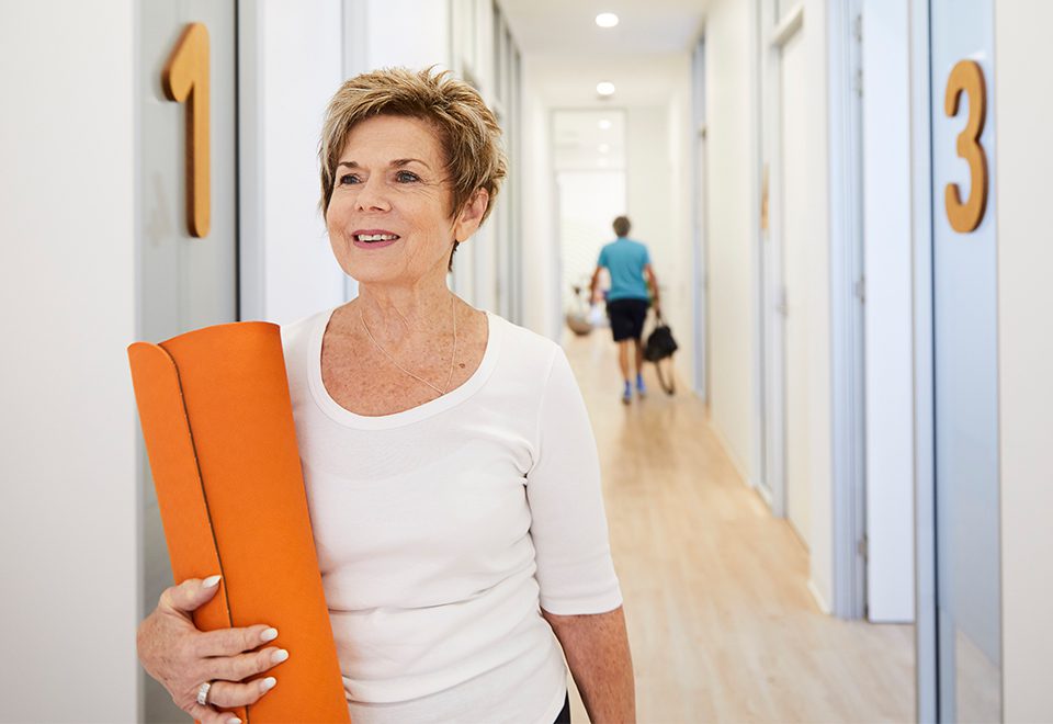 Health Studio customer heading to an exercise class, holding a yoga mat.