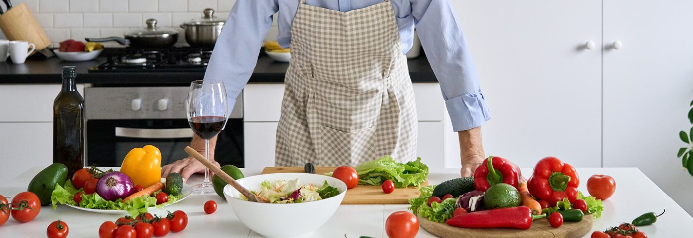 A man in the kitchen, deciding about what vegetables he should chop next