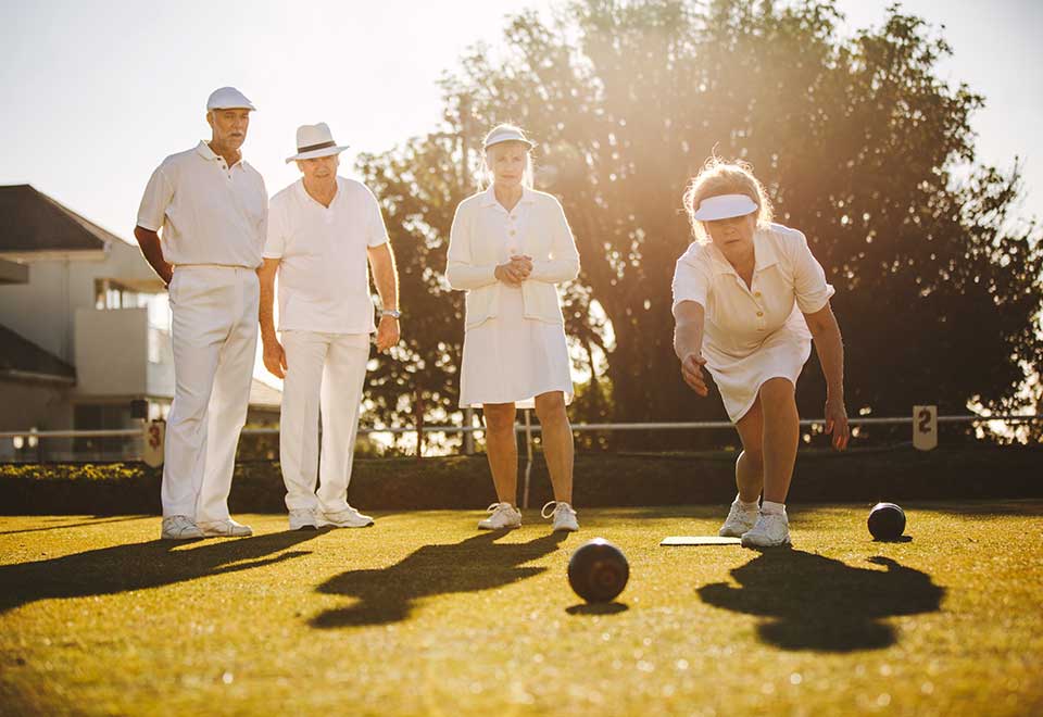 Group of happy older people playing lawn bowls