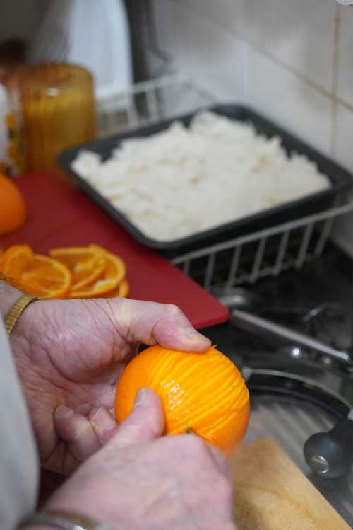 John peeling oranges into very thin half-moons for his orange cake.