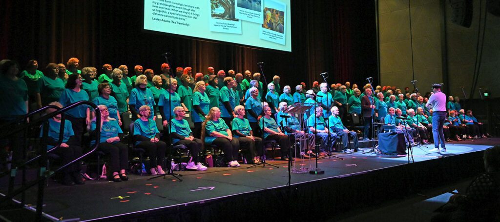 Passport to Song Concert photo with a choir singing and Paul Sinkinson conducting