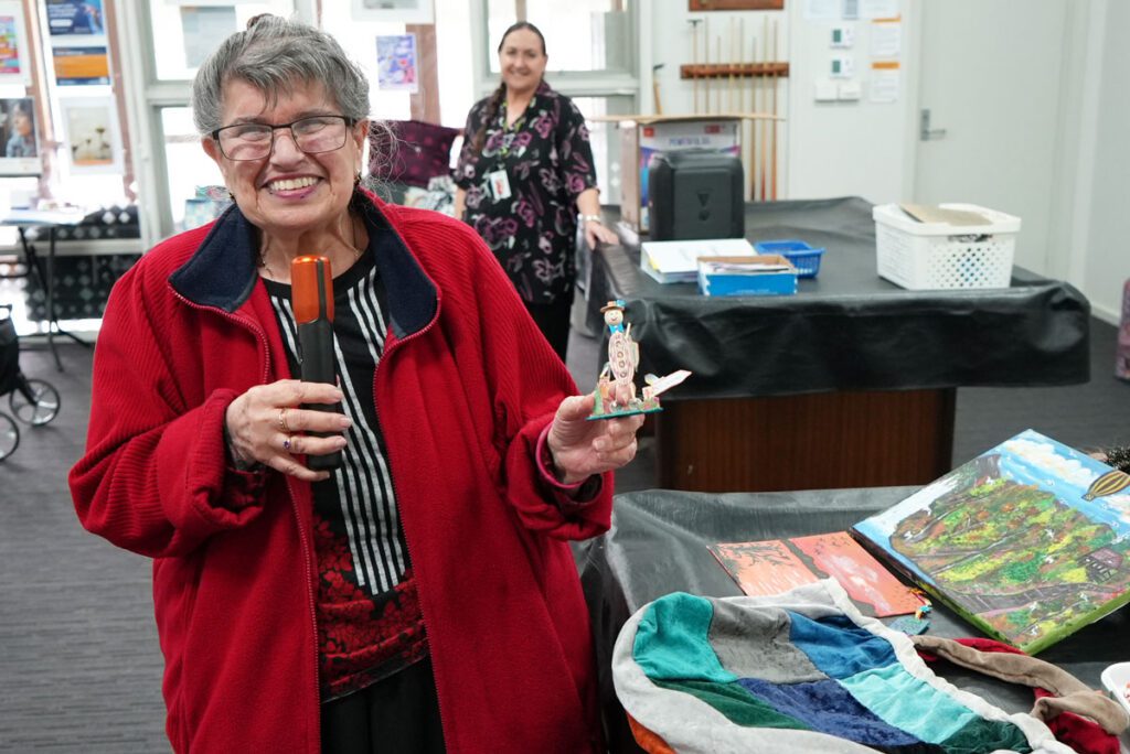 Ramona proudly shares one of her handmade creations, a reflection of the creativity and joy she brings to the group.