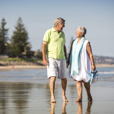 Old couple taking a walk at the beach and getting active