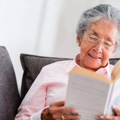 Older Asian lady enjoying reading a book