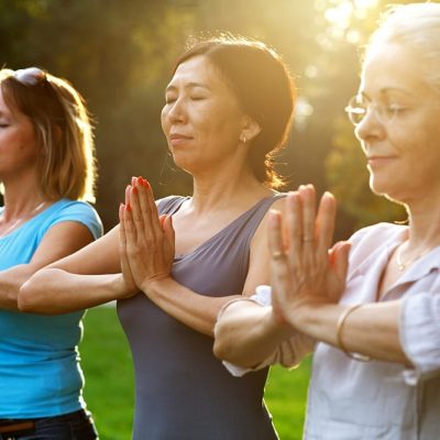 Women doing yoga in the park enjoying retirement living lifestyle